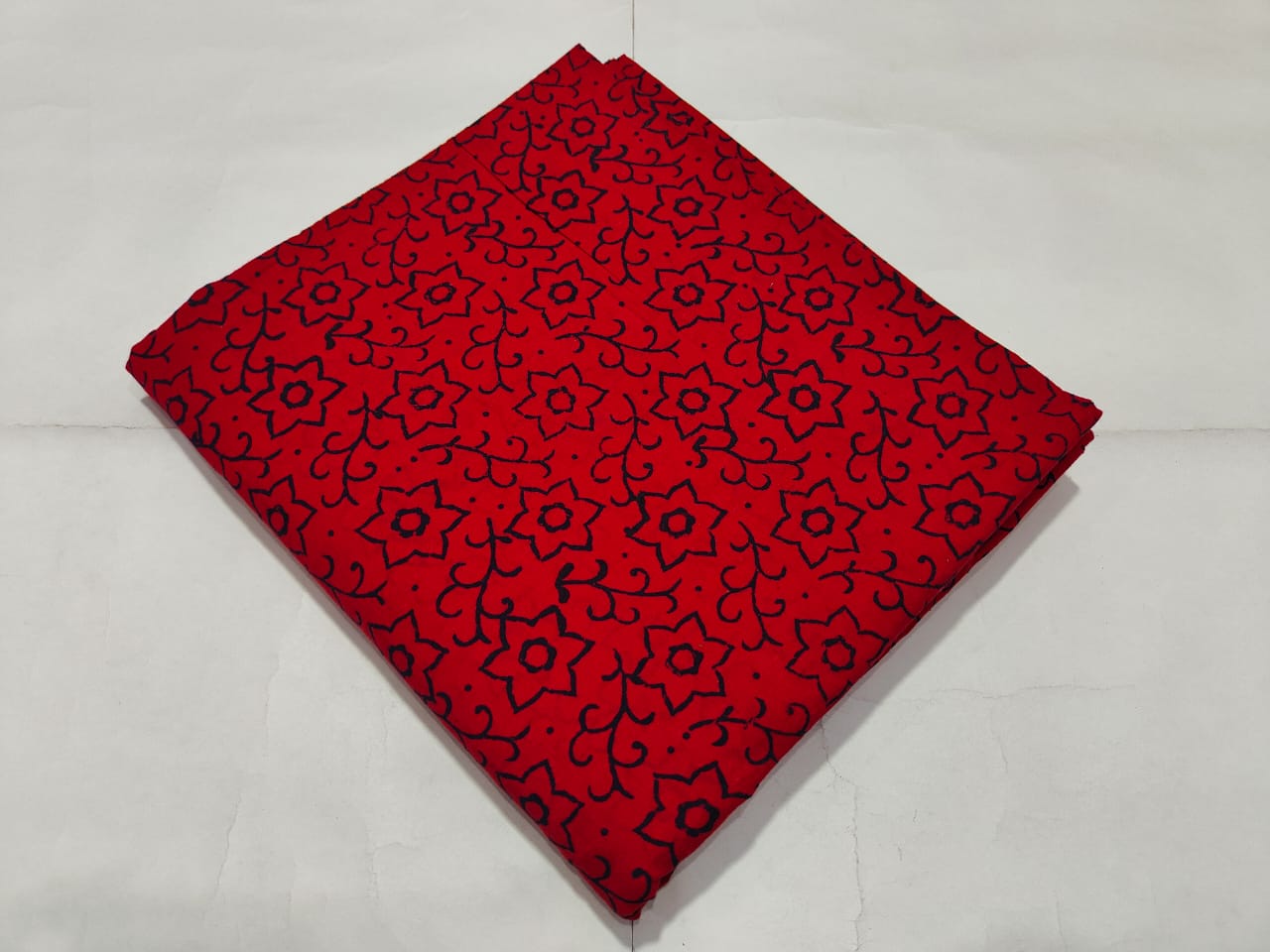 Red fabric with black pattern on a light gray background