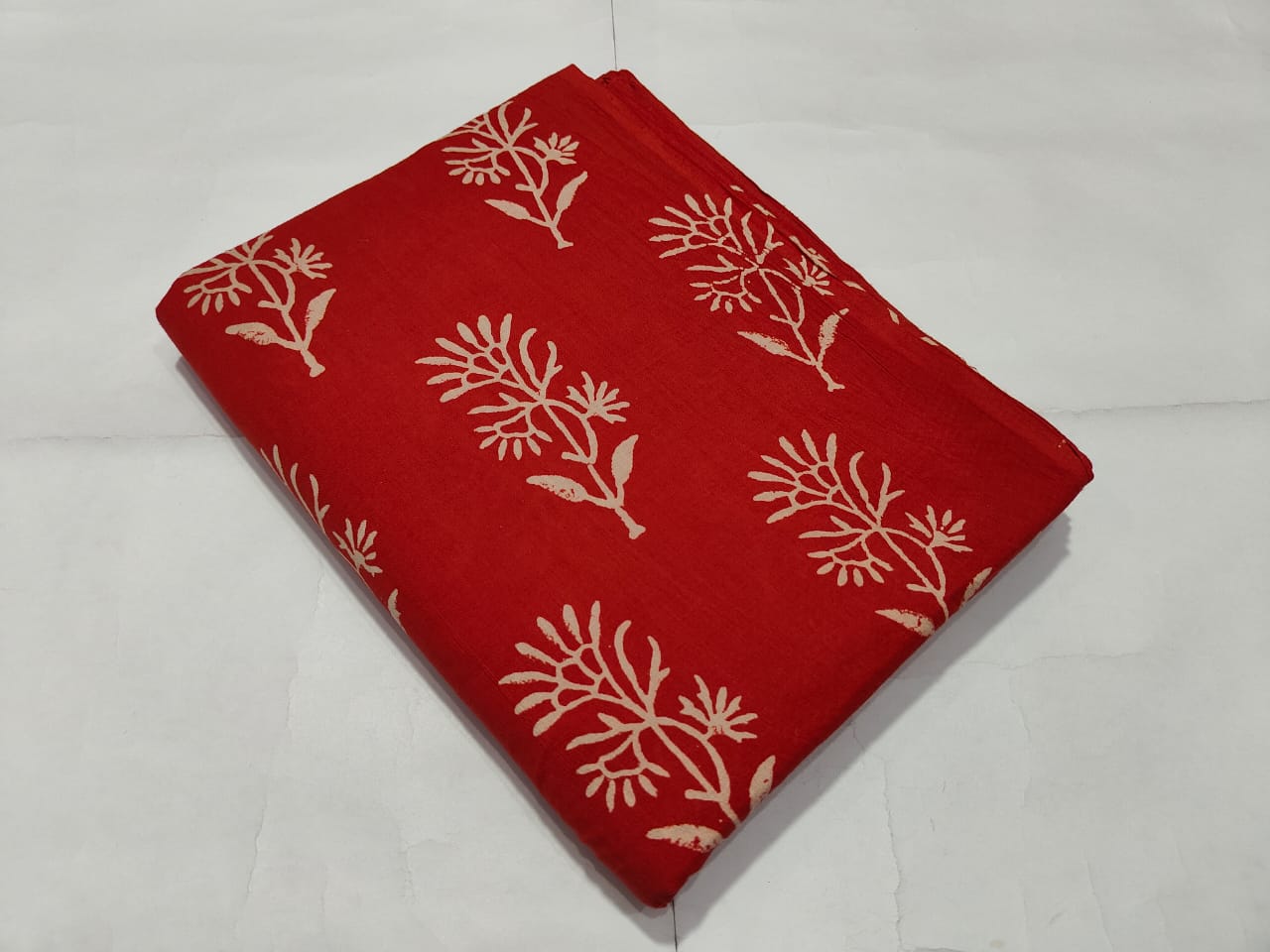 Red fabric with white floral patterns on a white background